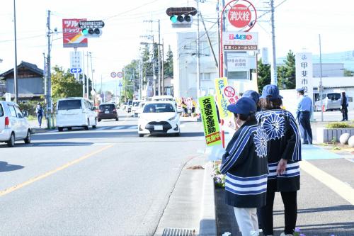 通行する車に啓発運動をする人の写真