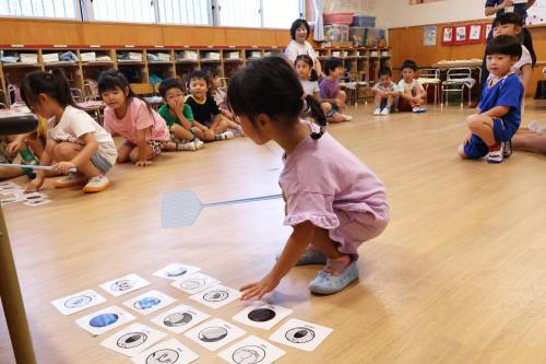 床にあるイラストの描かれたカードを選ぶ子どもの写真