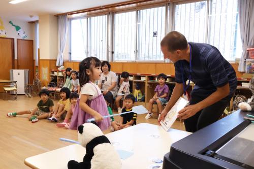 カードに書かれたイラストを英語で話す子どもの写真