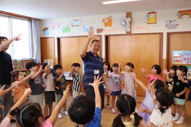 手を挙げる講師と子どもたちの写真