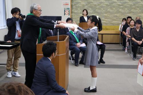 表彰状を受け取る小学校中学年の女子