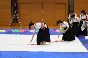 大きな紙に筆で書いていく高校生たち