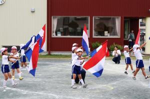 赤白青の旗を振って演技する園児たちの写真