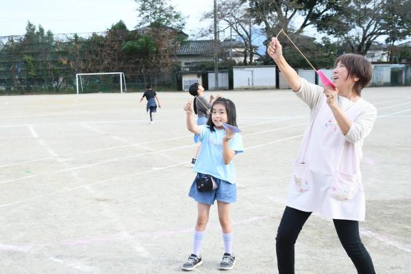 発射台と使って紙飛行機を飛ばす児童と先生