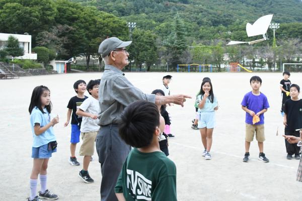 羽根をばたつかせて飛ぶ飛行機を飛ばす講師