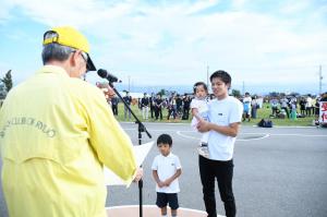 ラジオ体操の街フォトコンテストの表彰状を受け取る3人の親子
