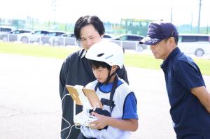 ドローンの送信機をのぞき込む男の子