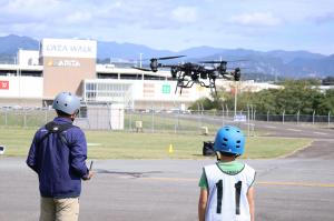 大型ドローンを操縦する講師とそれを見る男の子