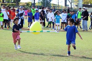 二本の棒を使ってボールを運ぶ競技をする二人の子ども