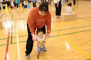 お母さんに両手を支えてもらいながら歩く乳幼児