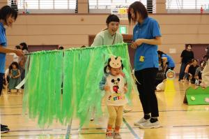 緑色のビニールテープでできたカーテンをくぐる女の子