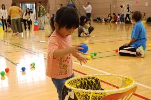 青色のボールをゴールに入れる女の子の写真