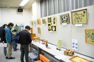 絵や工作物の展示を見学する人たち