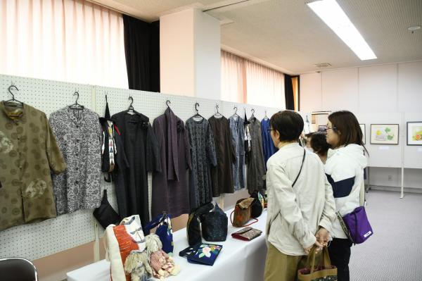 壁に展示された衣服を見る女性たち