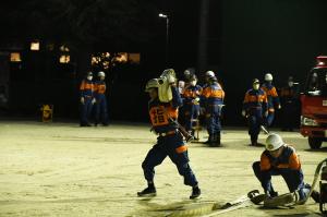 市消防団訓練総見、ホースを肩に担いで運びます