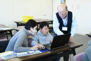 講師に操作を方法を教えてもらっている親子の写真