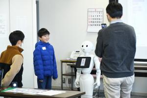 ペッパー君にプログラミング通りの指示がとおり満足そうにしている子どもの写真