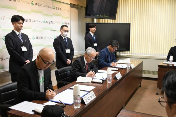 協定書に署名する三者