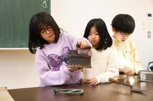 炭火アイロンを手にする女の子の写真