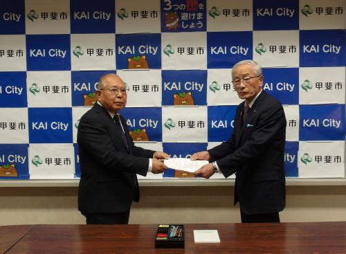 水道審議会会長から市長へ答申案を手渡ししている様子