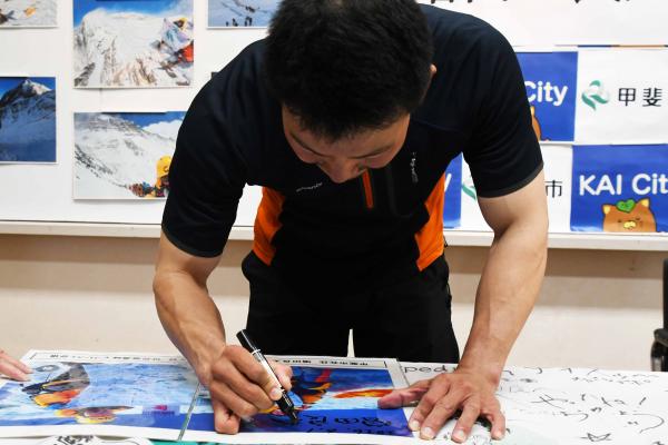 登頂写真にサインを書き込む増田さん