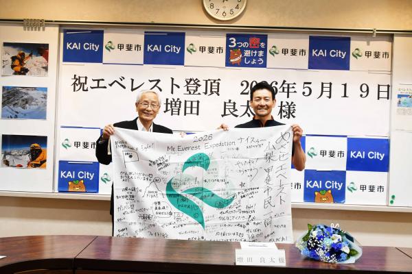応援メッセージが書き込まれた甲斐市旗を市長と増田さんで