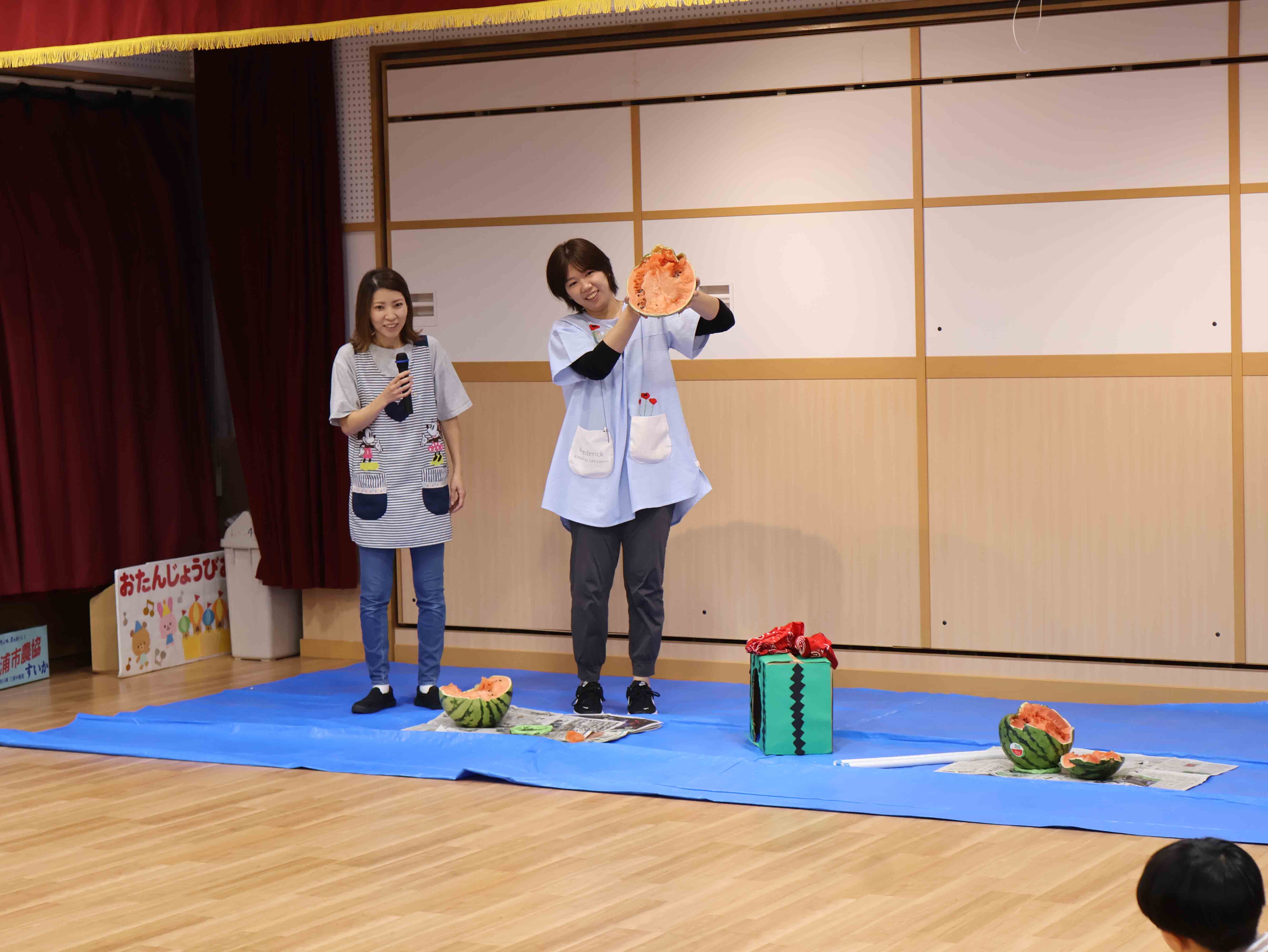 割れたスイカを見せる先生