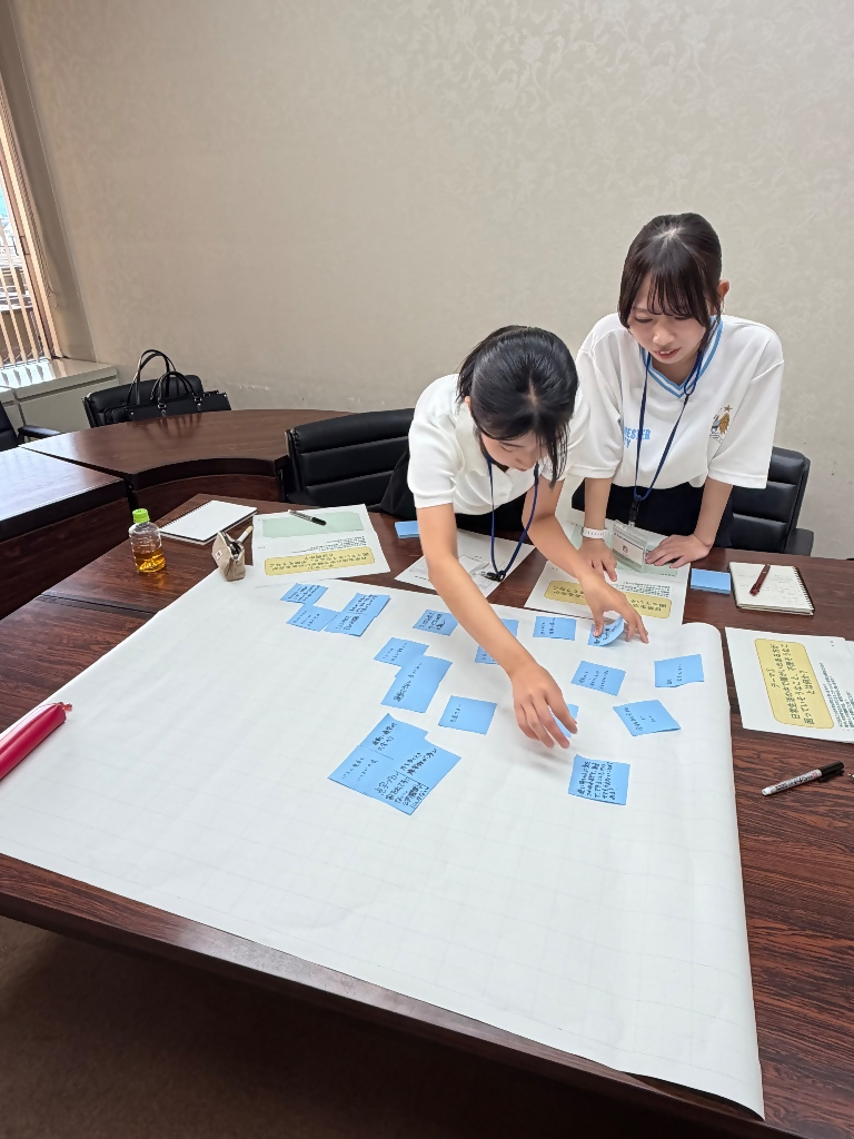 出たアイディアを模造紙にまとめる学生