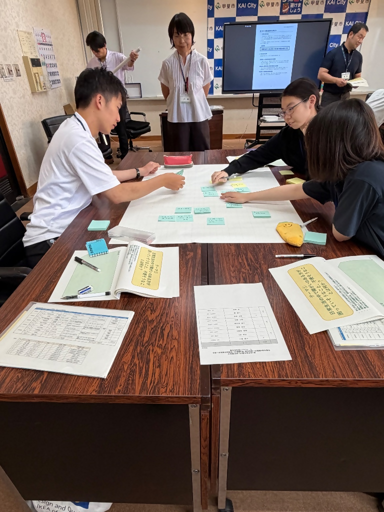 出た意見を模造紙に貼り付ける学生